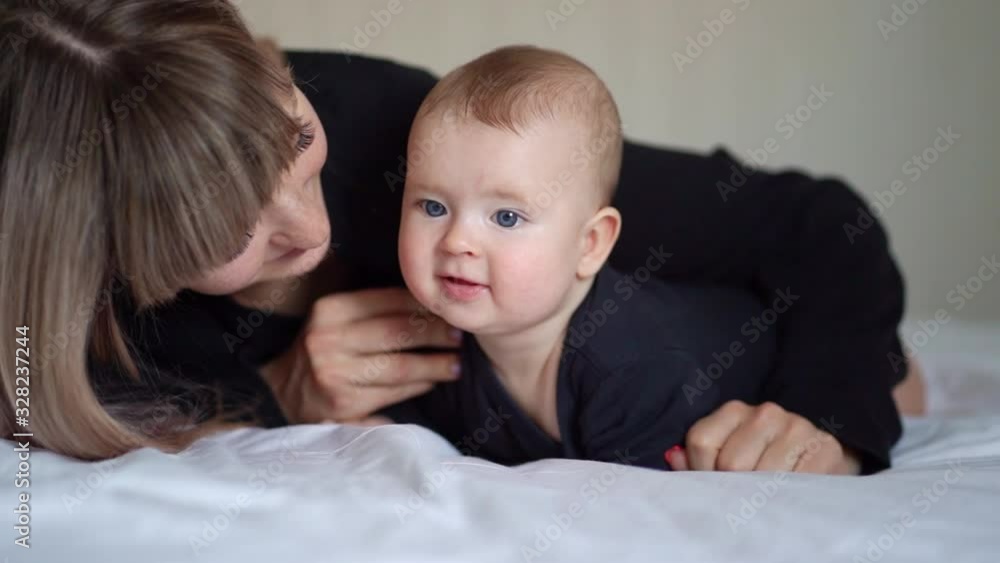 the mother kisses her son lying on the bed the mother kisses her son lying on the bed