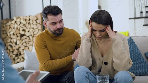 Front view of young unhappy married couple visiting the psychologist office to get consultation because they have problems in relations