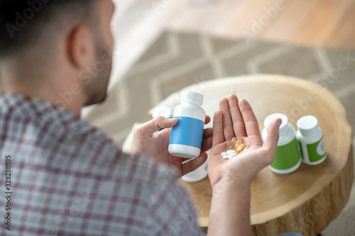 Young man in a checkered shirt hoding pills