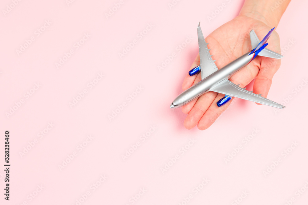 Beautiful young woman's hands holding plane on pastel background . Beautiful young woman's hands holding plane on pastel background .