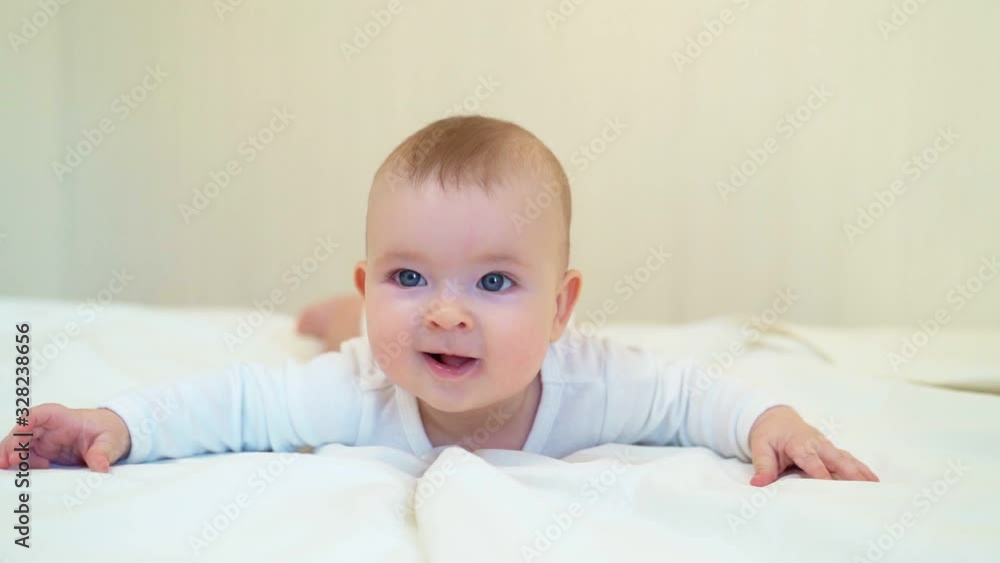 baby in white lying on paunch on white bed baby in white lying on paunch on white bed