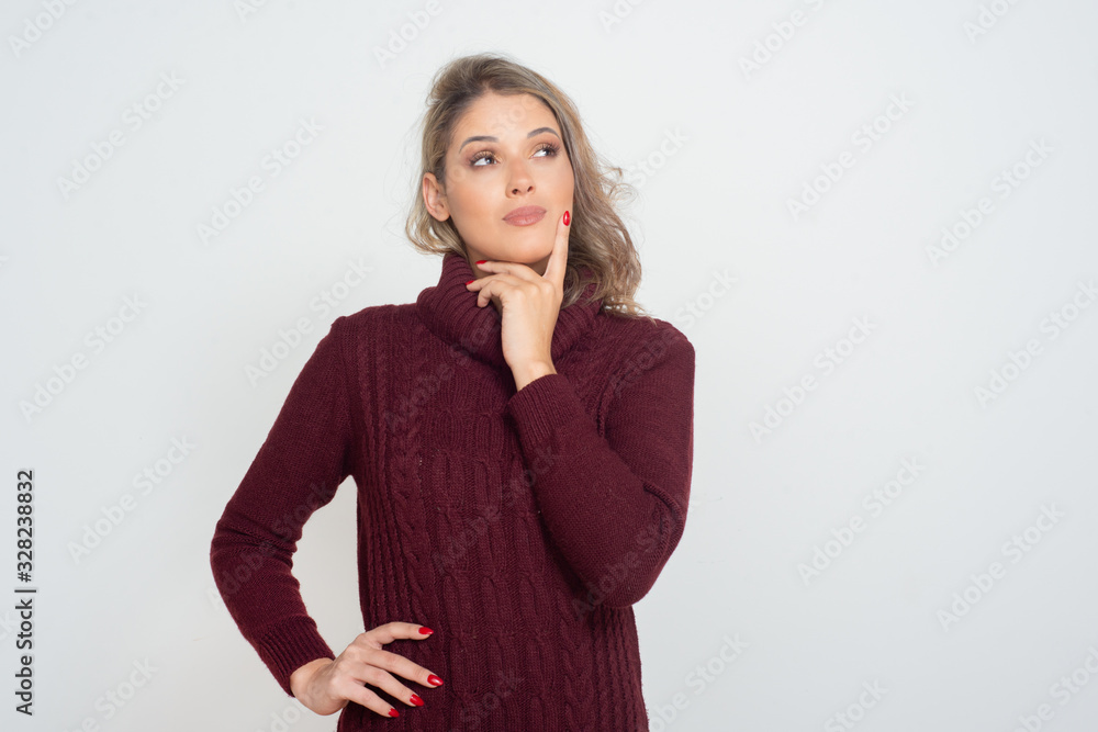 Pensive young woman looking aside. Portrait of beautiful thoughtful young blonde woman standing with finger on chin and looking away isolated on white background. Thinking concept Pensive young woman looking aside. Portrait of beautiful thoughtful young blonde woman standing with finger on chin and looking away isolated on white background. Thinking concept