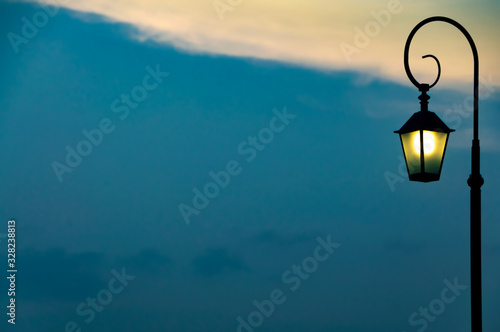 View of silhouette of classic street lamp post lighting against twilight sky