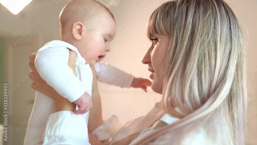 mother holding baby in front of him and kisses him mother holding baby in front of him and kisses him