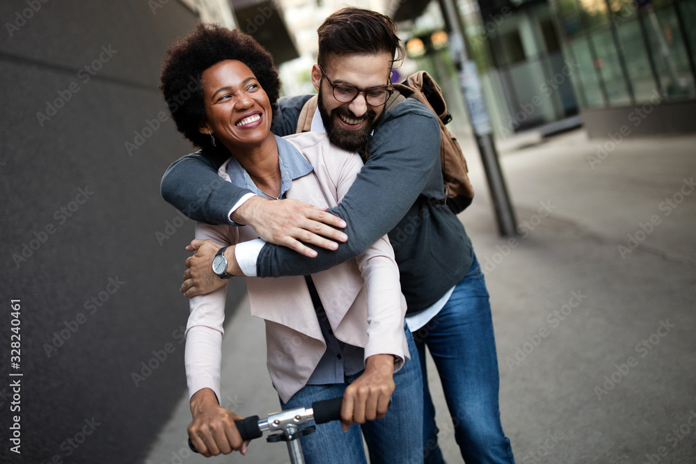 Happy young couple enjoying together while riding electric scooters on city street - obrazy, fototapety, plakaty 