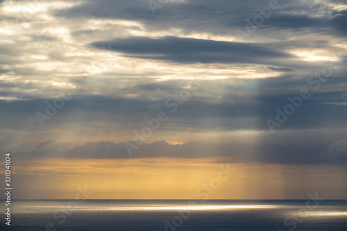 Long aerial view of gray evening clouds over Tasman sea coast at Piha with run rays