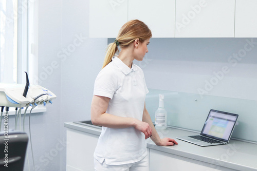 Obraz na plátně Woman dentist keeps a record of customers in her laptop