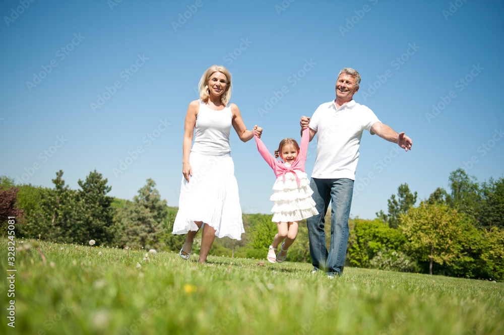 Happy senior couple with child in a park Happy senior couple with child in a park