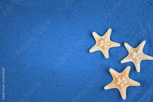  Starfish on the blue sand copy space. Colored sand.