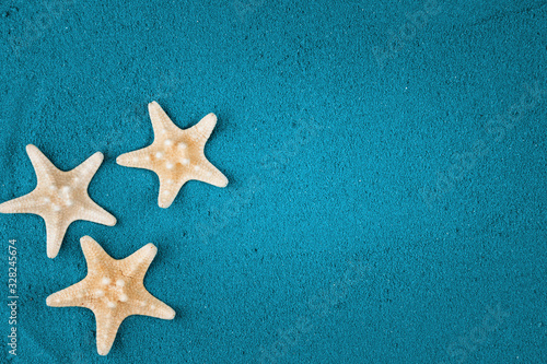  Starfish on the blue sand copy space. Colored sand.