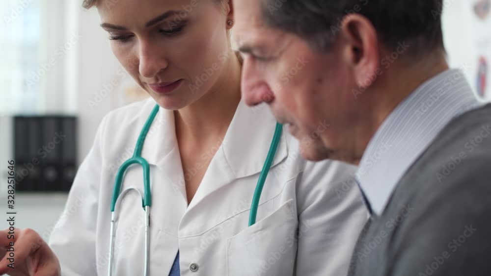 Handheld view of doctor and patient analyzing the medical results in doctor office. Shot with RED helium camera in 8K Handheld view of doctor and patient analyzing the medical results in doctor office. Shot with RED helium camera in 8K