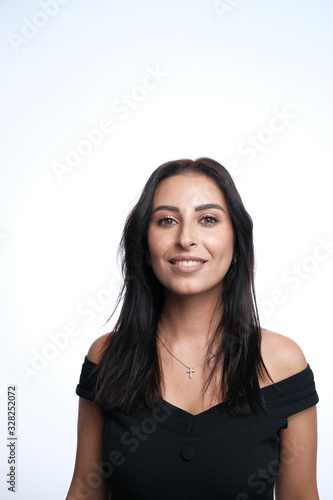 A large portrait of a middle-aged woman  30-35 years old  with dark hair and brown eyes in a black dress on a light background.