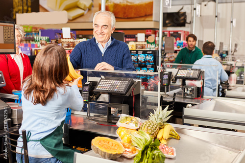 Customer at the supermarket cashier pays for fruit