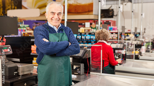 Senior as a cashier at the supermarket cashier photo