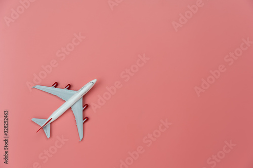 Table top view accessory of accessory travel in holiday background concept.Flat lay of white airplane on modern rustic pink paper at home studio office desk.copy space for creative design text.