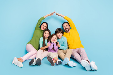 Portrait of nice attractive lovely charming cheerful big full family sitting mom dad making roof new apartment move relocation isolated on bright vivid shine vibrant blue color background