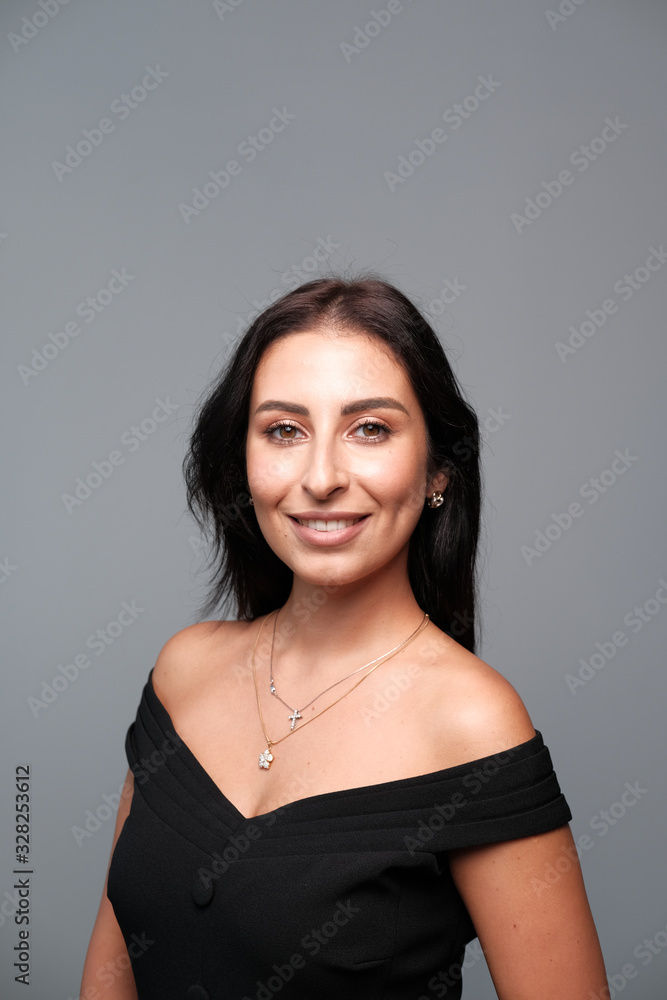 A large portrait of a middle-aged woman (30-35 years old) with dark hair and brown eyes in a black dress on a light background. A large portrait of a middle-aged woman (30-35 years old) with dark hair and brown eyes in a black dress on a light background.