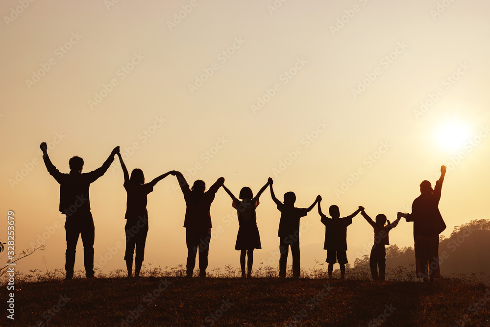 Silhouette of happy family standing with raised hands on the mountain at the sunset time. Silhouette of happy family standing with raised hands on the mountain at the sunset time.