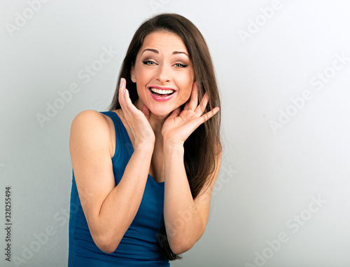 Beautiful positive excited young woman with smiling face in blue shirt and long hair on blue background