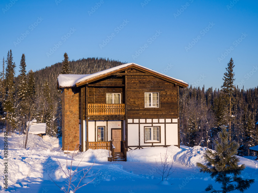 Wooden two-story Alpine-style house. Hotel in the ski resort Gornaya Salanga. Winter day