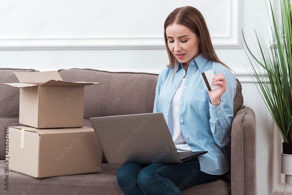 Woman looking at her laptop and holding credit card Woman looking at her laptop and holding credit card