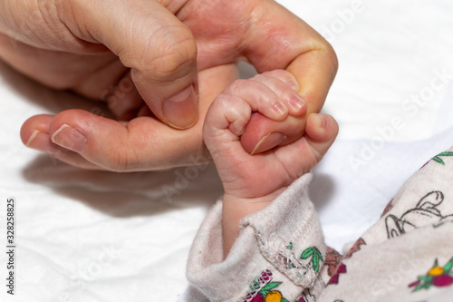 Close up and main focus on Newborn baby holding mother's hand