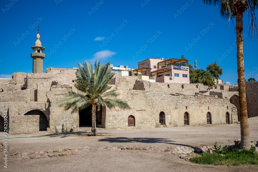 Tourists can walk on fortress walls. Court yard view of Aqaba Castle. The main fort square is empty under the sunlight. Sunny winter day. Clear cloudless blue sky