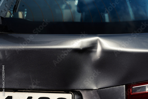 A dent in the body of a silver car