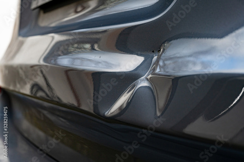 A dent in the body of a silver car
