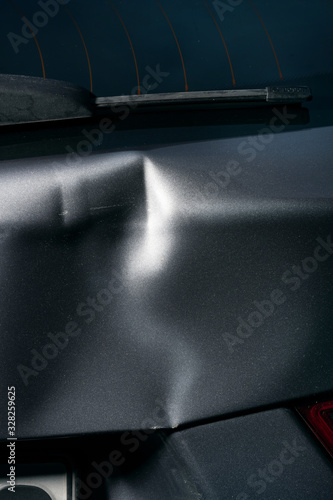 A dent in the body of a silver car photo