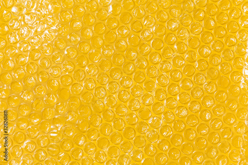 Bubble wrap top view on yellow background.