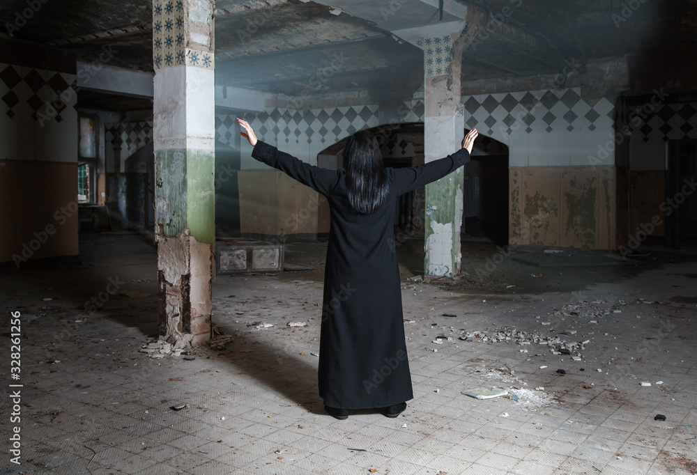gothic brunette woman raising her hands standing in large empty hall
