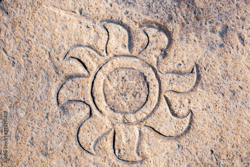 sun drawing sign in the rocks sand beach background