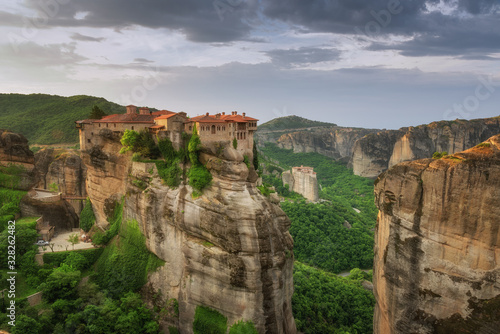 Beautiful scenic view, Holy Orthodox Monastery of Rousanou (St. Barbara) and Varlaam, bright green foliage at the background of stone wall in Meteora, Pindos Mountains, Thessaly, Greece, Europe