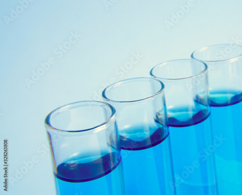 Test glass tubes with blue liquid, macro, selective focus. Laboratory test tubes. test tube with liquid sample on light blue background, closeup. Medical concept. 