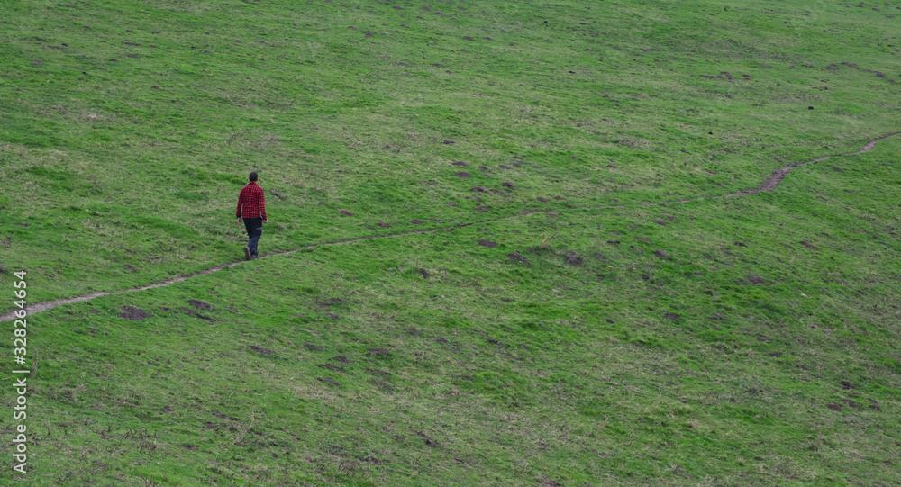 Hiker walking through a green meadow, Mount Jaizkibel. Basque Country Hiker walking through a green meadow, Mount Jaizkibel. Basque Country