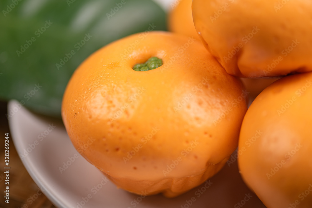 Pork dumpling in cartoon style,Pork bun like an orange in a white plate on the indoor dining table Pork dumpling in cartoon style,Pork bun like an orange in a white plate on the indoor dining table