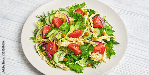 Fresh salad with cherry tomatoes, savoy cabbage, cucumeber on dish. Healthy summer salad vegetarian meal concept. Tasty mixed leaves, tomatoes and mix vegetable salad on white wood