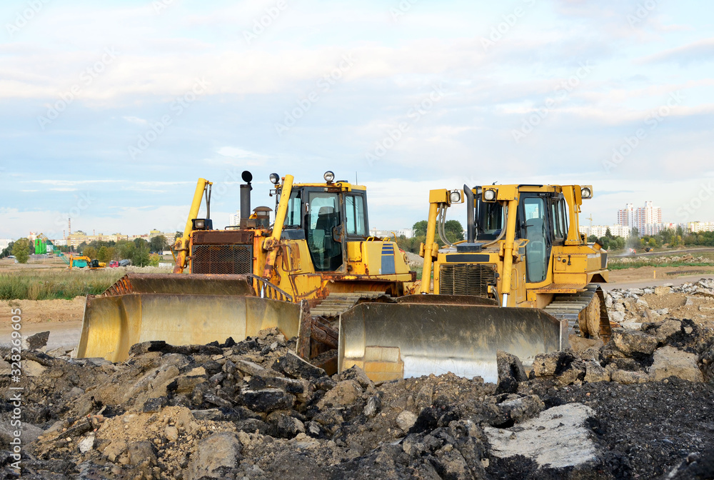 Obraz premium Track-type bulldozer, earth-moving equipment. Land clearing, grading, pool excavation, utility trenching, utility trenching and foundation digging during of large construction jobs.
