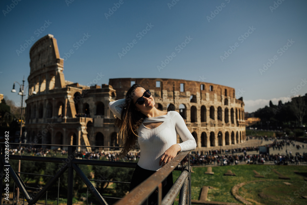 Famous Colosseum in Rome, Italy. Travel girl smiling and posing against Roman colosseum. Spring holidays and vacation in Europe.