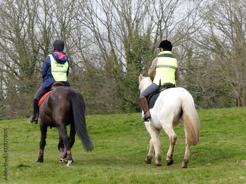 Two women, wearing high visibility jackets, riding horses on Chorleywood Common in Hertfordshire, England, UK © Peter Fleming