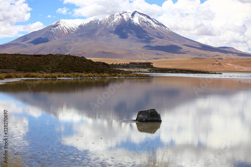 Bolivia desert in Potosi province, Andes highlands. Beautiful lake with clear and calm waters. Desert rustic scenery with arid soil, mountains and cloudy sky. Off road adventure.