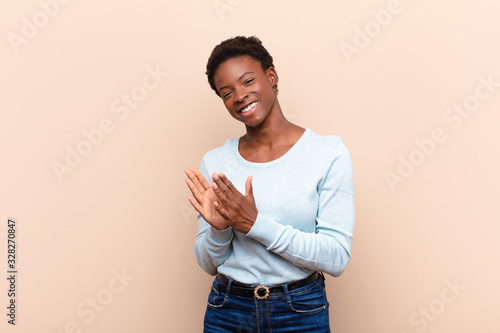 young pretty black womanfeeling happy and successful, smiling and clapping hands, saying congratulations with an applause photo