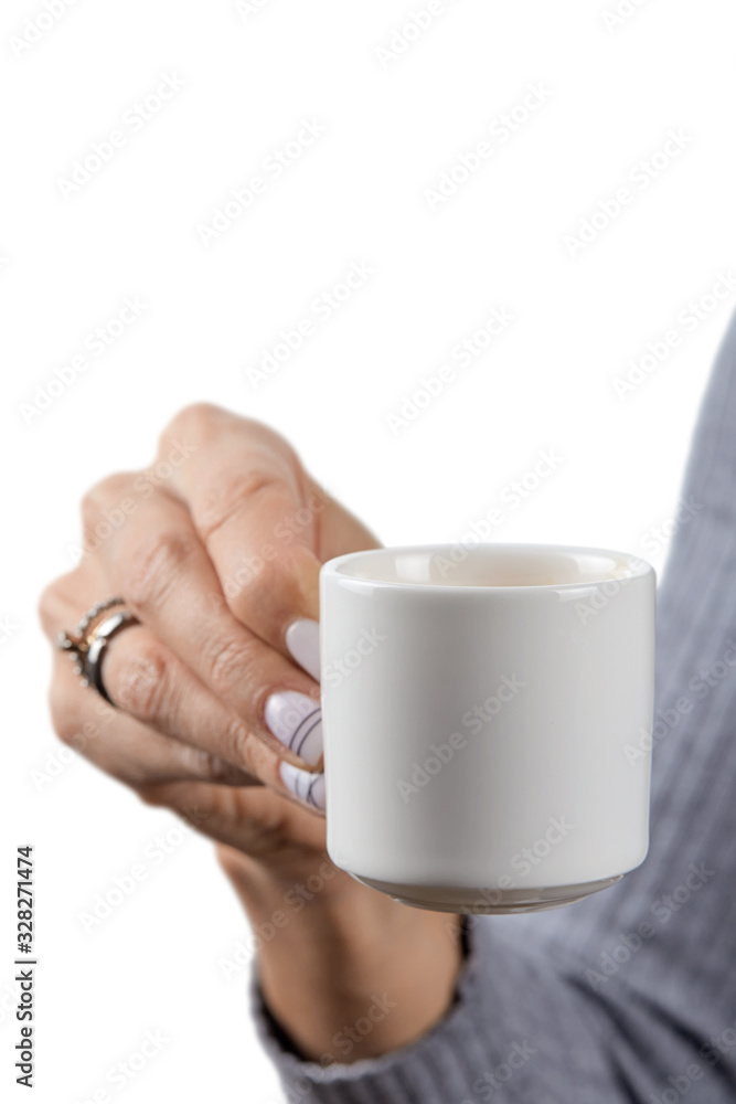 Cup of freshly brewed espresso in a beautiful elegant hand with a manicure and rings of a European girl in a grey wool sweater isolated on a white background. Cup of freshly brewed espresso in a beautiful elegant hand with a manicure and rings of a European girl in a grey wool sweater isolated on a white background.