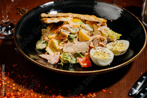 Caesar salad on black plate on wooden table