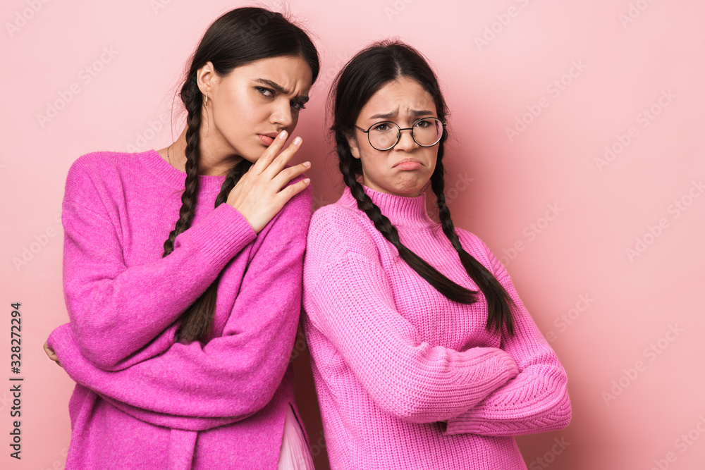 Image of two upset teenage girls with braids gossiping together Image of two upset teenage girls with braids gossiping together