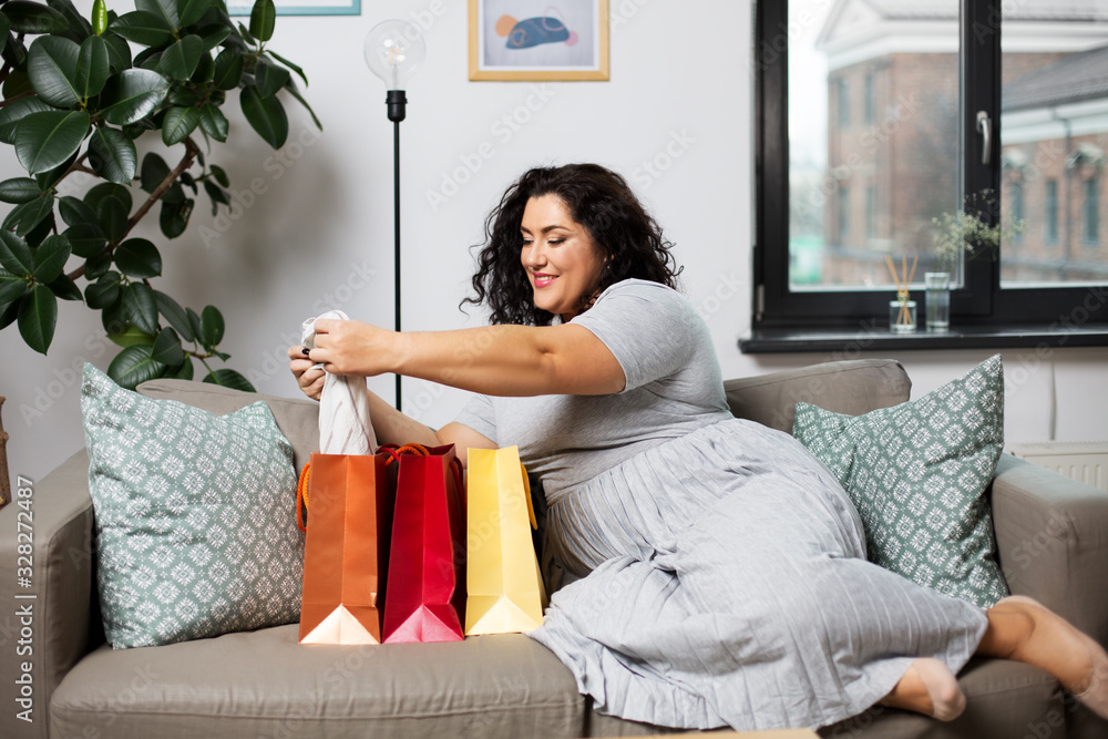 people and leisure concept - happy smiling young woman with shopping bags on sofa at home people and leisure concept - happy smiling young woman with shopping bags on sofa at home