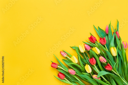 Bouquet of red and yellow tulips on bright yellow background. Beautiful greeting card. Holidays concept. Copy space, top view photo