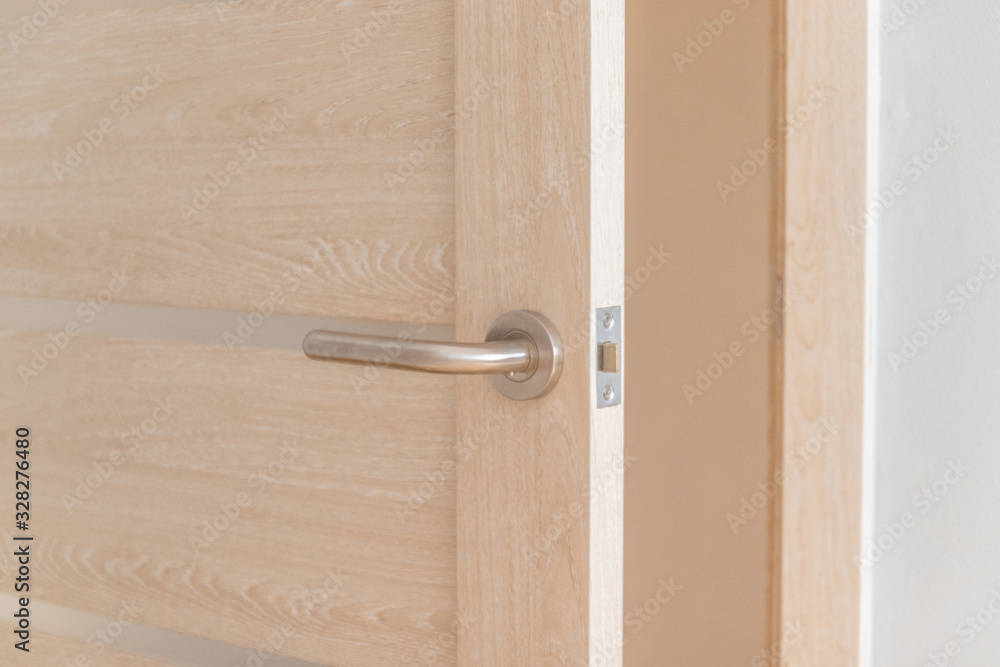 Open bright wooden door with a lock and a metal handle in a hotel or apartment room Open bright wooden door with a lock and a metal handle in a hotel or apartment room