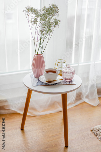 Spring home cozy interior. A bouquet of flowers in a vase  a cup of tea  decor on a coffee table.